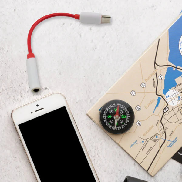 Smartphone with USB adapter, compass, and map on a light surface