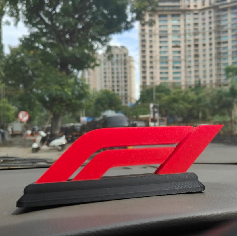 Red car emblem on a car dashboard with a cityscape in the background