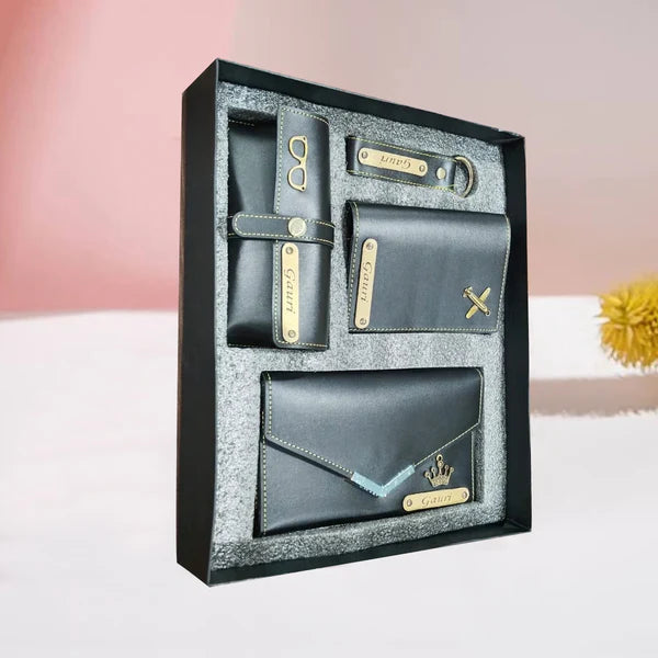 Set of black wallets with gold accents in a decorative box on a light pink background.