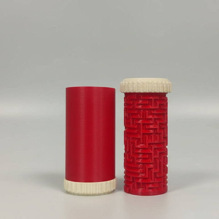 Two cylindrical objects, one red with a textured pattern and one plain red, on a reflective surface.