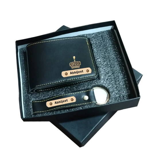 Black leather wallet and keychain set with 'Abhijeet' branding in a box on a textured surface.
