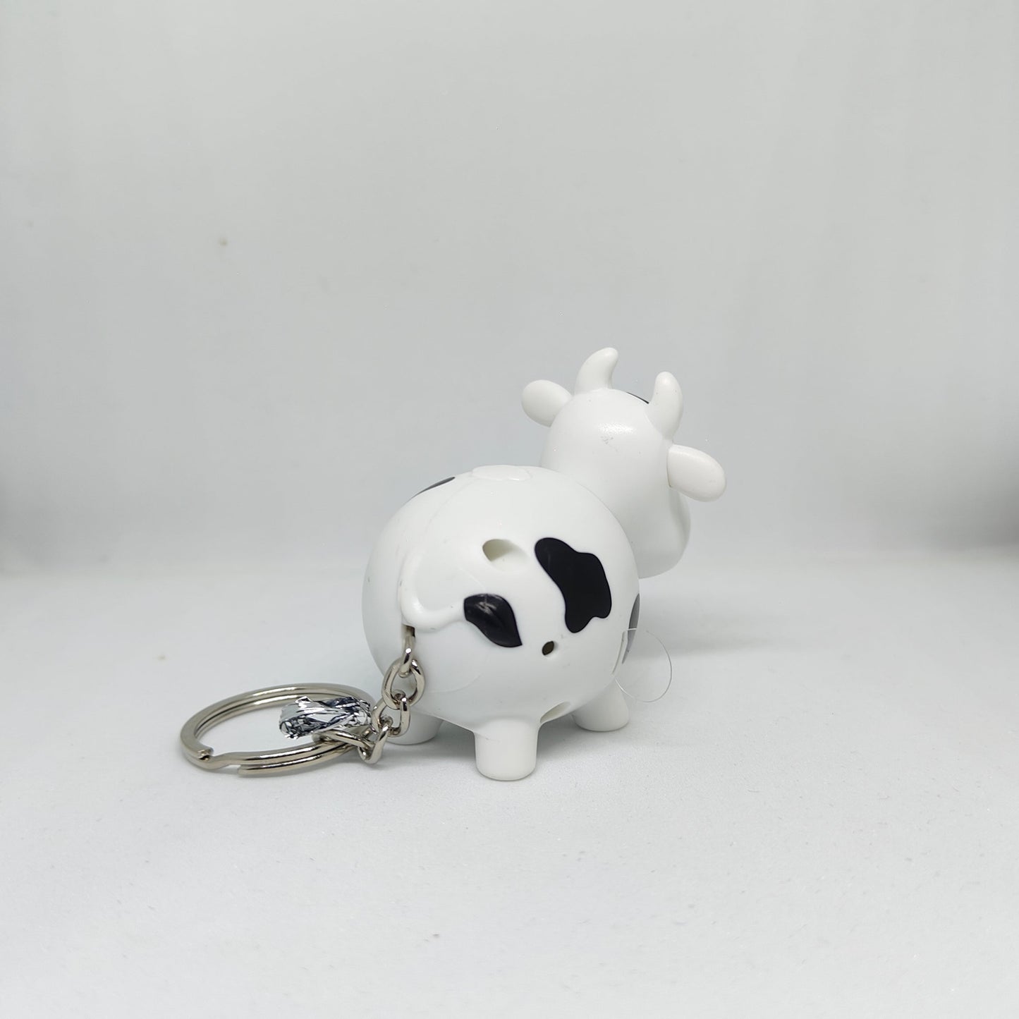 White cow-shaped keychain with black spots on a white background