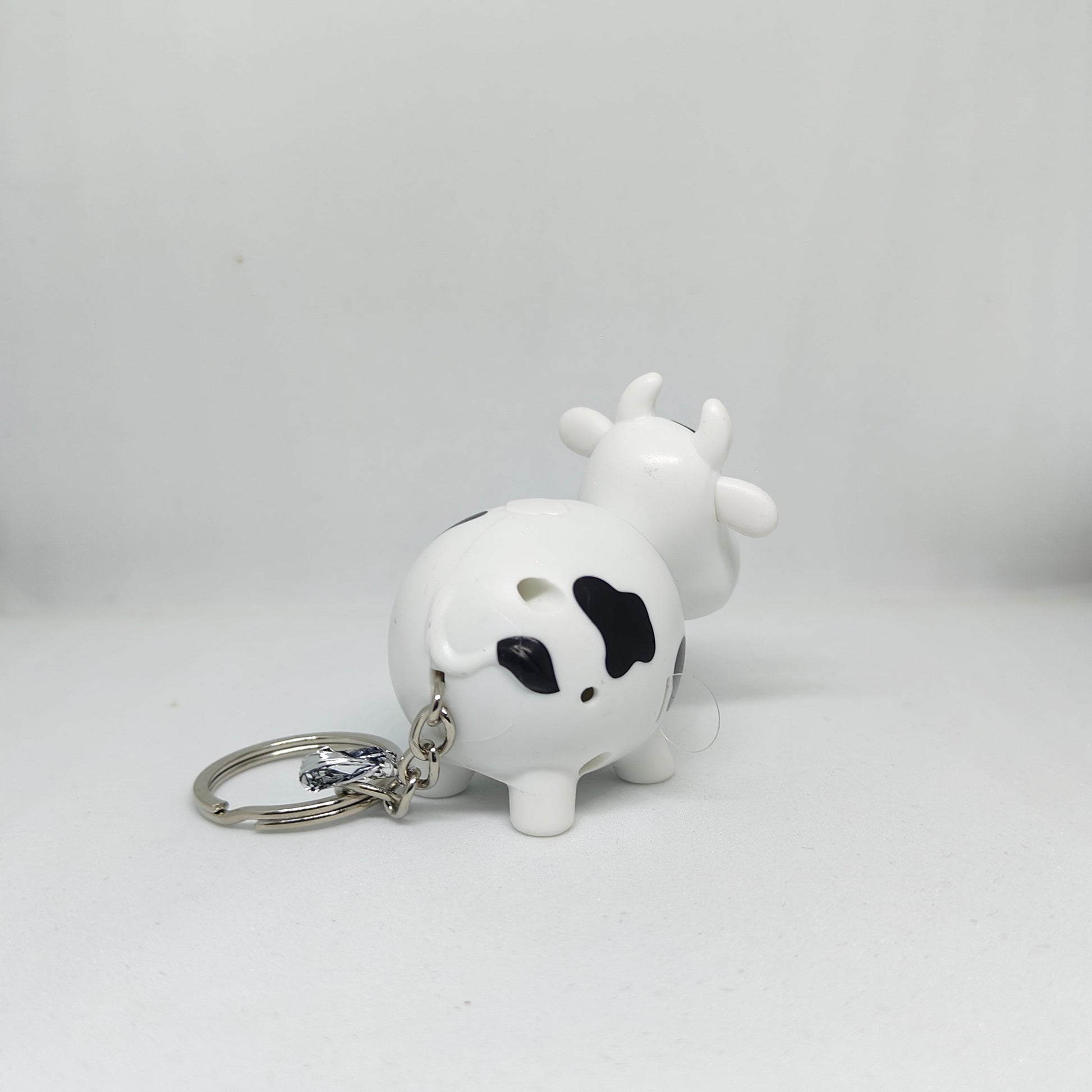 White cow-shaped keychain with black spots on a white background