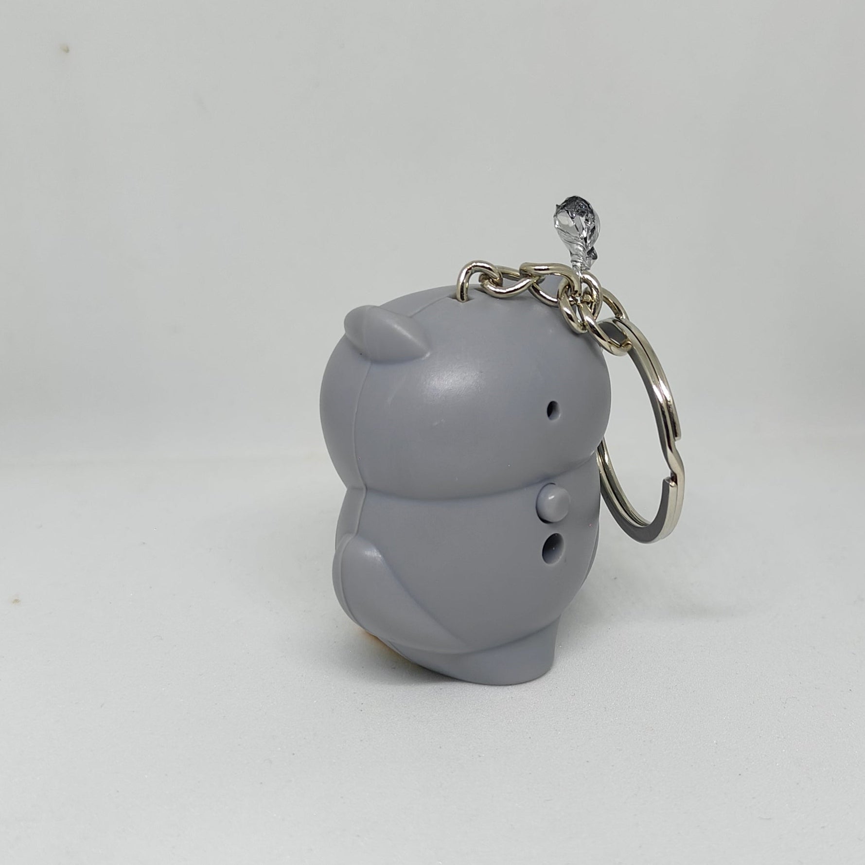 Gray cat-shaped keychain on a white surface