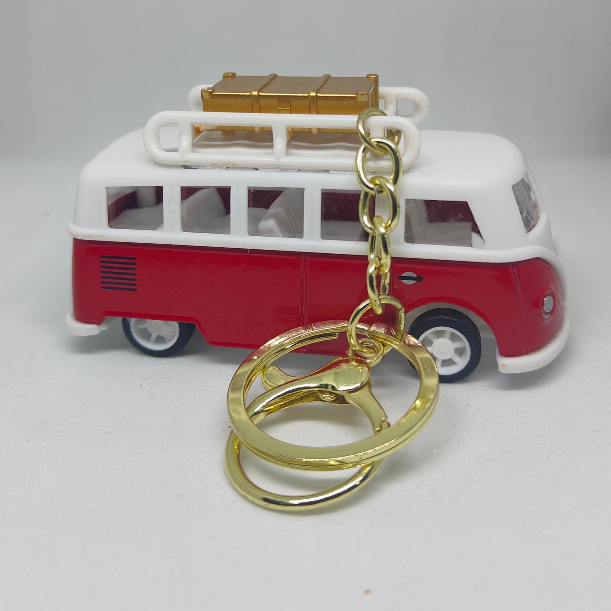 Red and white van-shaped keychain with gold chain on a light gray background