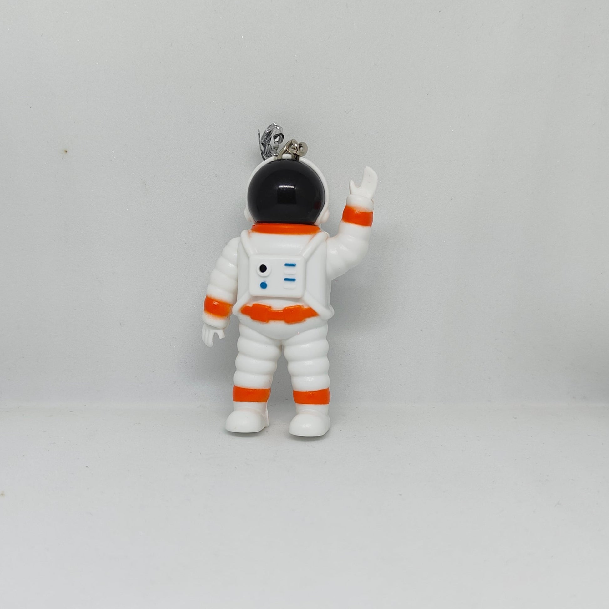 Small figurine of an astronaut in a white suit with orange accents on a gray background